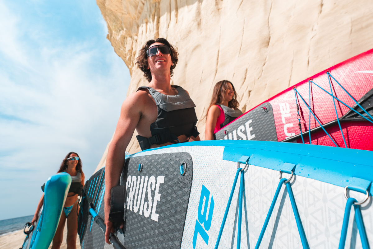 three people holding bluefin cruise paddleboards