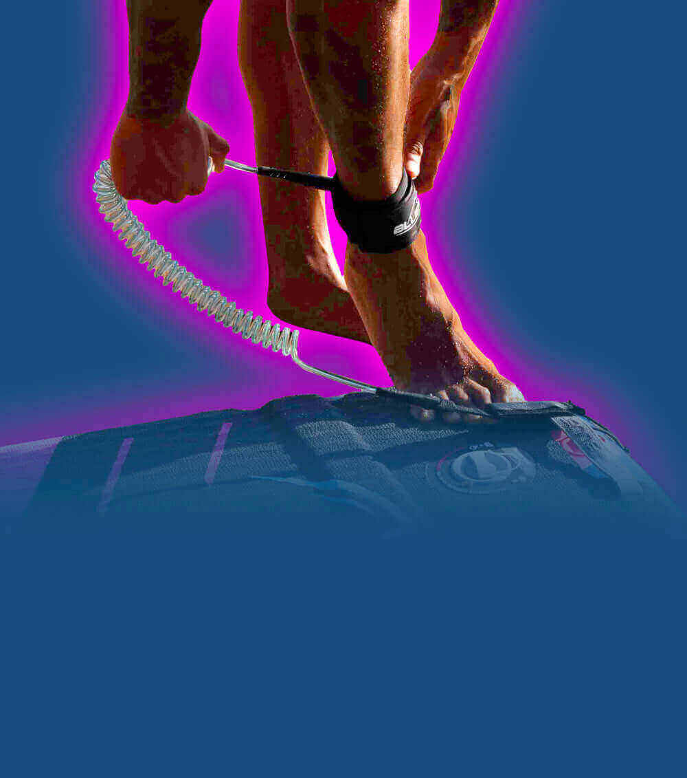 Person attaching a coiled leash to their ankle while standing on a paddleboard