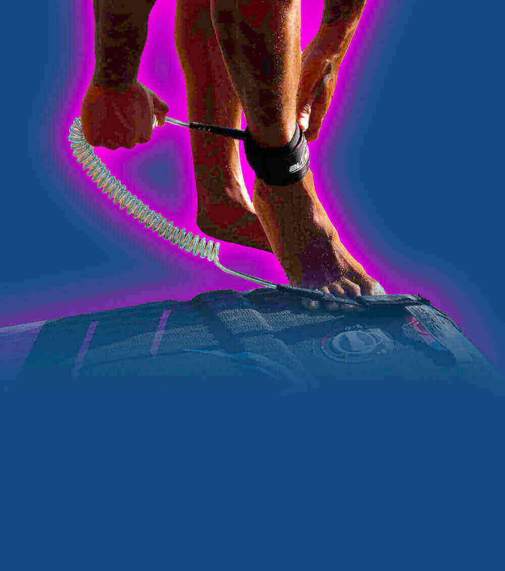 Person attaching a coiled leash to their ankle while standing on a paddleboard