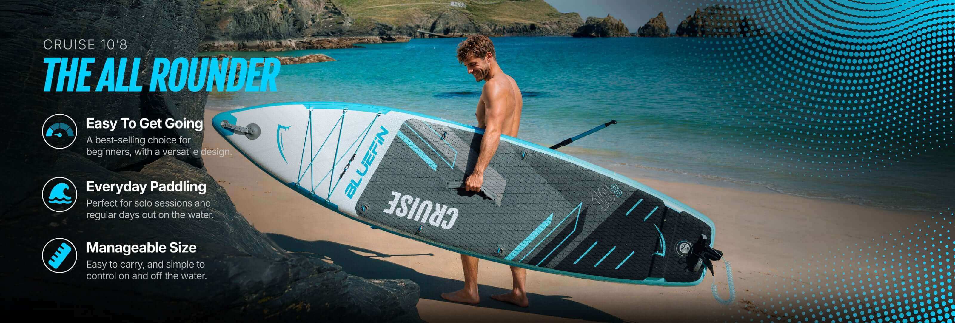 Man holding a Bluefin Cruise 10'8 inflatable paddleboard on a beach with rocky background.