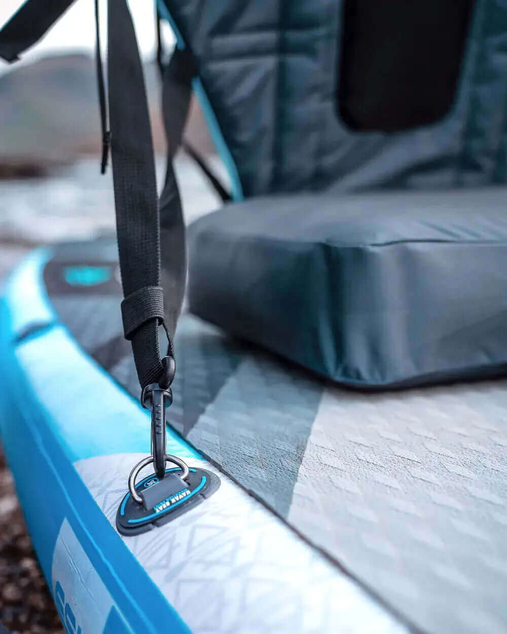 Close-up of a blue inflatable paddleboard with a seat, strap, and attachment point.