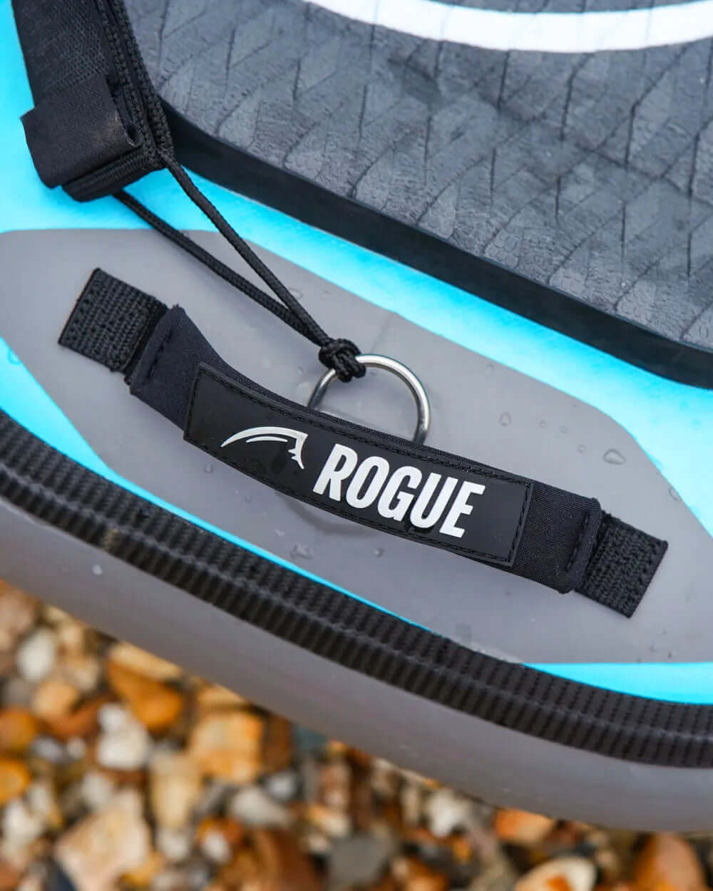 Close-up of a paddleboard handle with "ROGUE" label and metal ring, water droplets visible