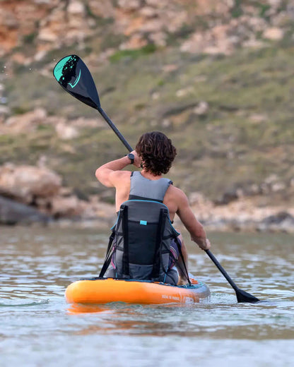 Person paddling an orange inflatable paddleboard with a black paddle on calm water