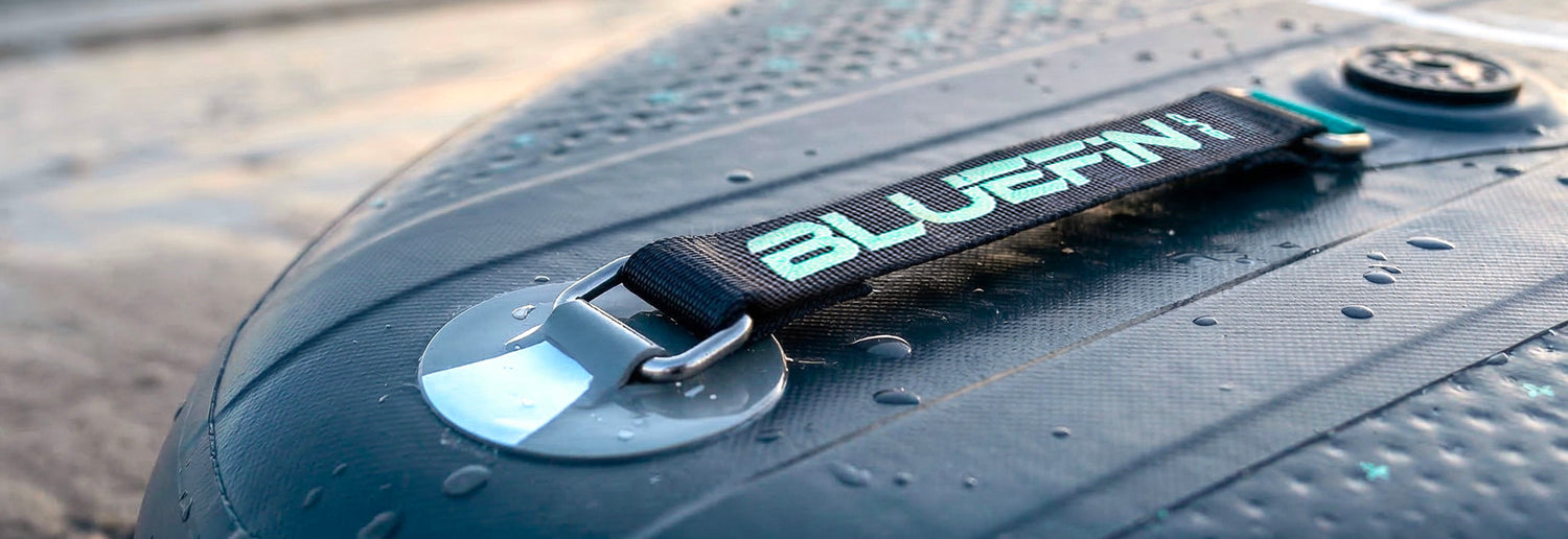 Close-up of a Bluefin SUP strap attached to a paddleboard with water droplets on the surface