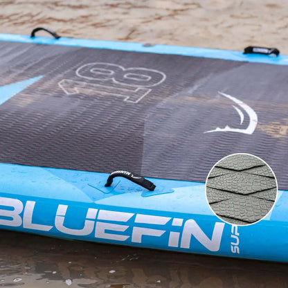 Opblaasbaar paddleboard met textuur op het dek, blauwe randen en middenvin op nat zand